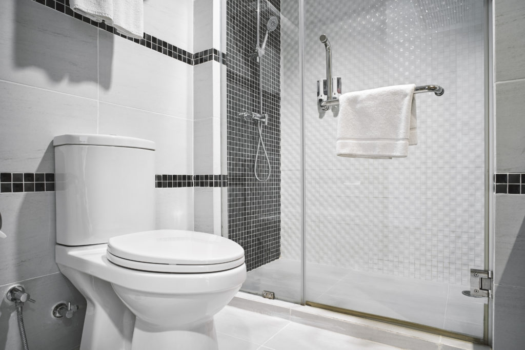 Toilet in a modern bathroom with white walls and gray accents