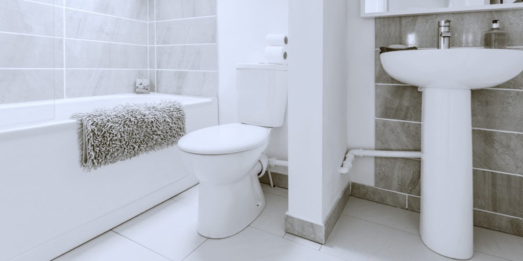 Small toilet in white bathroom with gray wall tiles