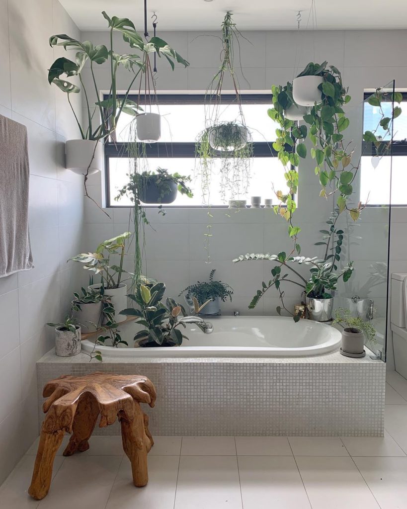 bathroom with many plants incorporated into it and natural wood stool Bathroom Lighting Ideas