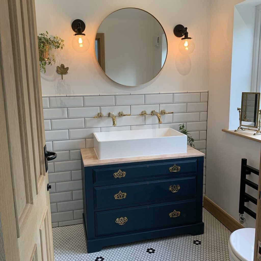 bathroom with navy blue vanity and circle mirror Bathroom Lighting Ideas