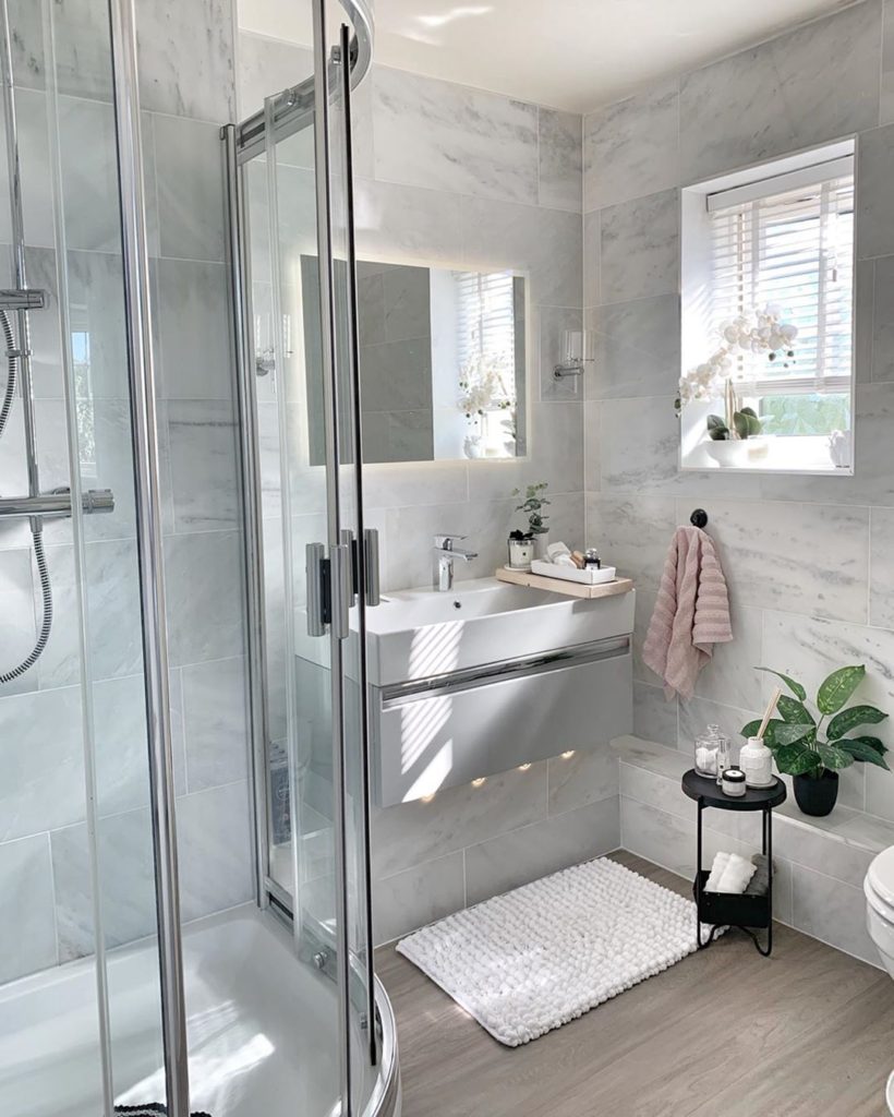 Bathroom with marble tile on walls with white rug