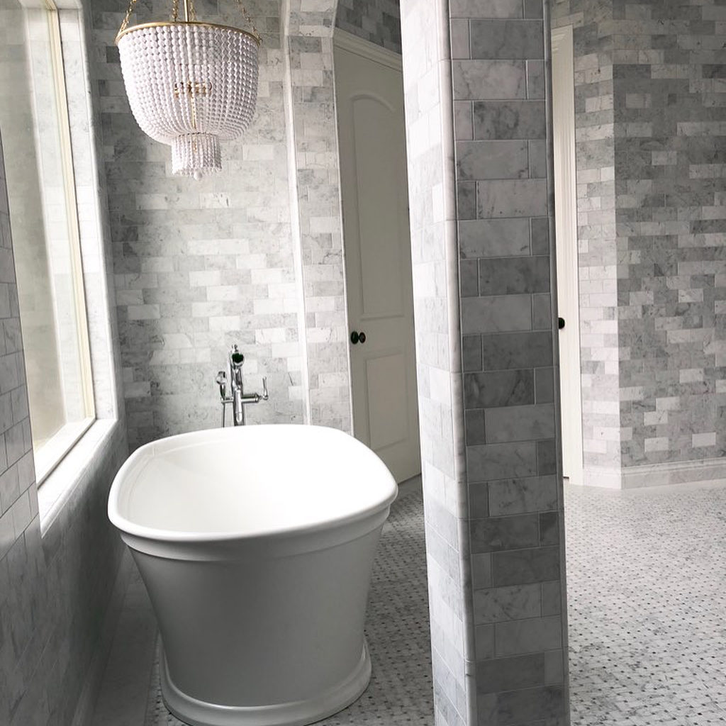 bathroom with natural stone on walls and bath tub chandelier