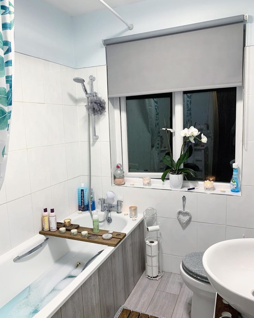 gray bathroom with bath tub and gray roller shade