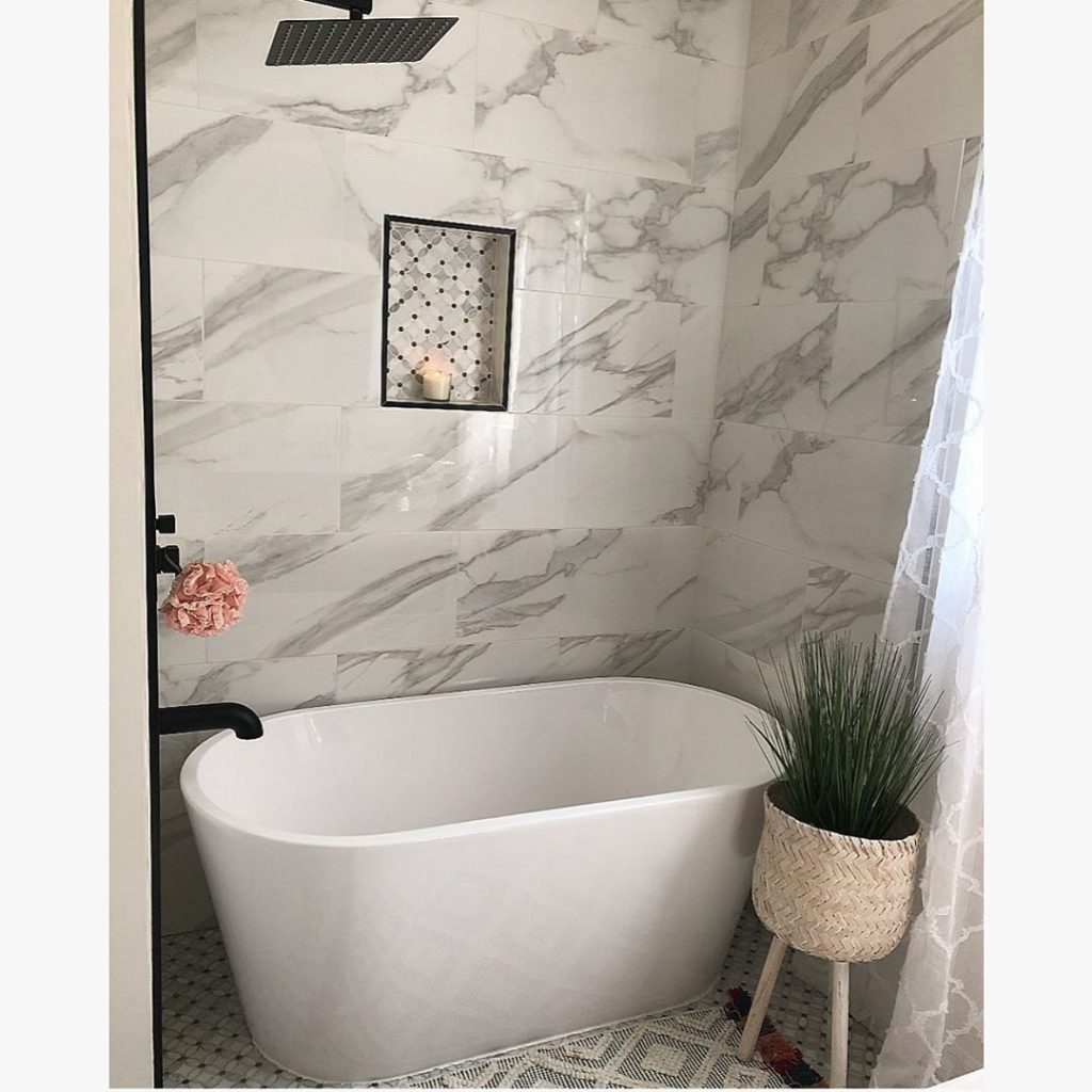 white bath tub with marble walls and black faucet