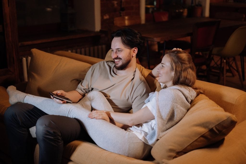 Couple cuddling lovingly in the center of a couch