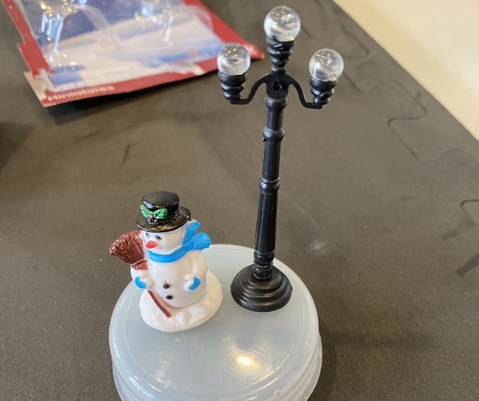 snow man figurine and lamp being glue down to snow globe base