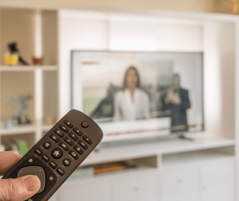 A person holding a remote control while watching TV