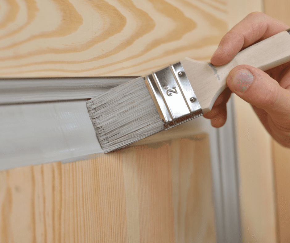 A person painting a door with a paintbrush