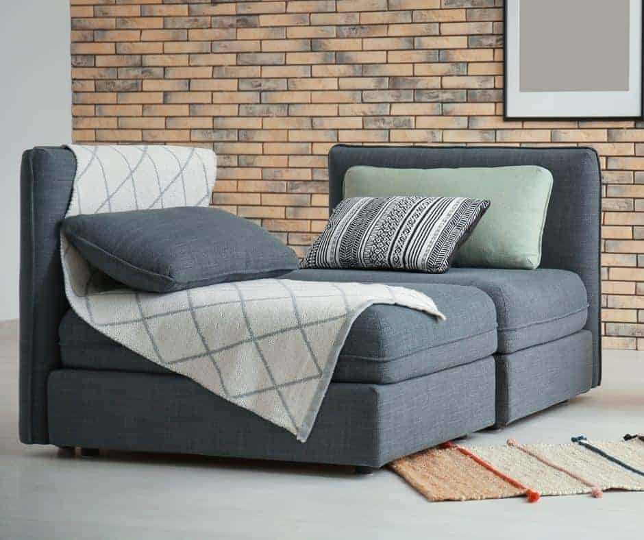 beautiful sectional in grey with a blanket on it