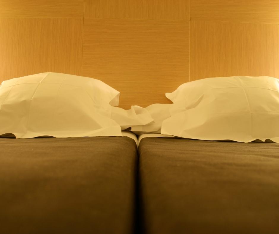 two twin beds resting next to each other with two white pillows on them