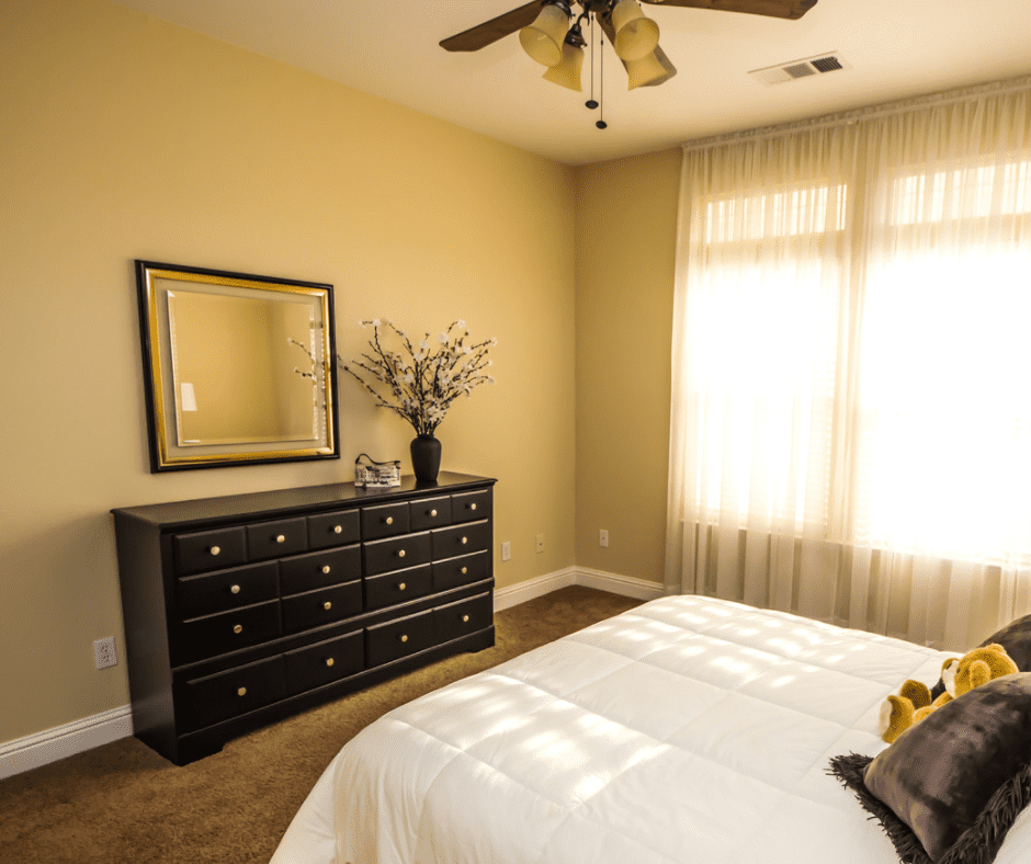 Stylish modern black dresser under a framed mirror in a bedroom