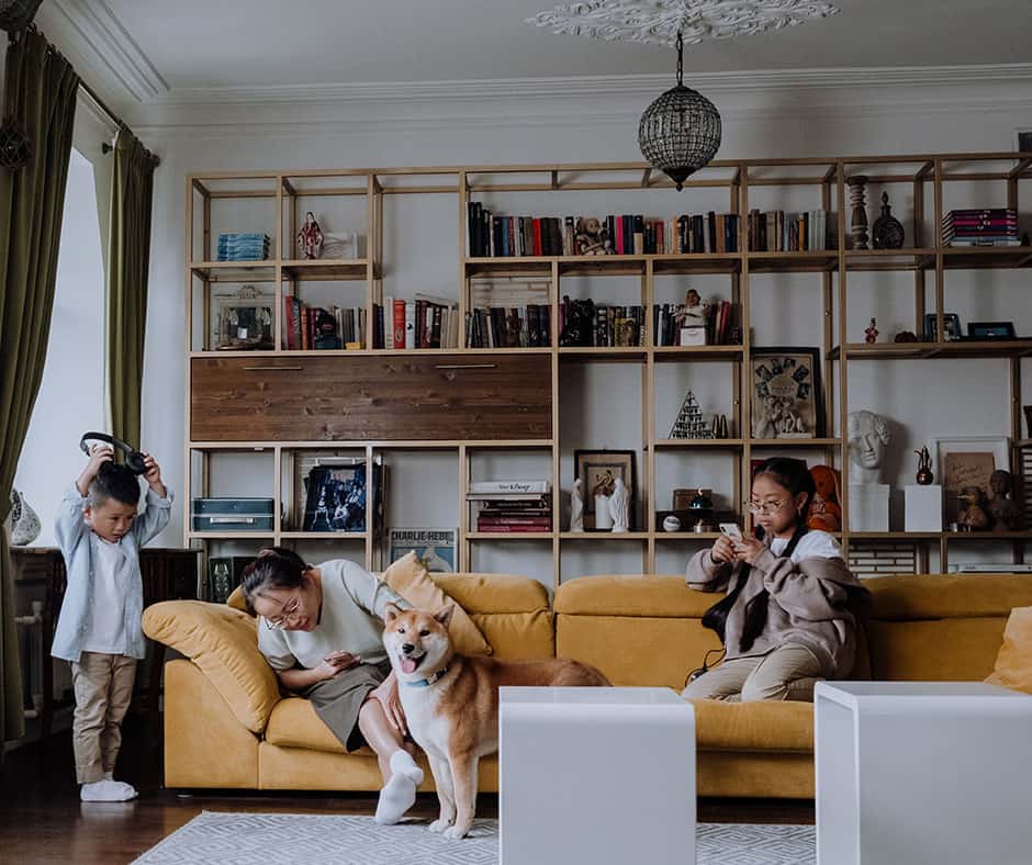 Mom, kids, and dog in and around a beige sofa