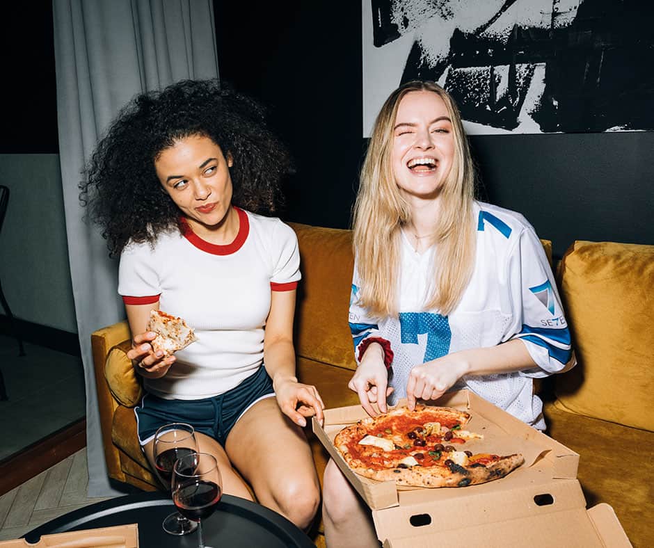 Girls eating while on a beige sofa