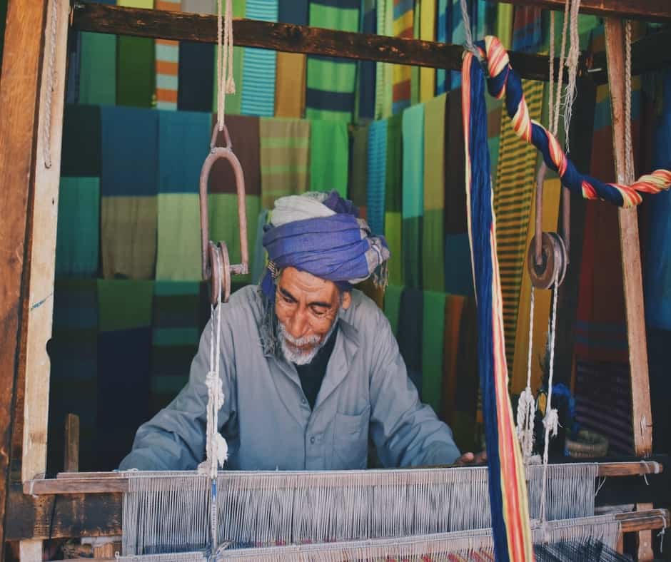 Man weaving a rug using a loom