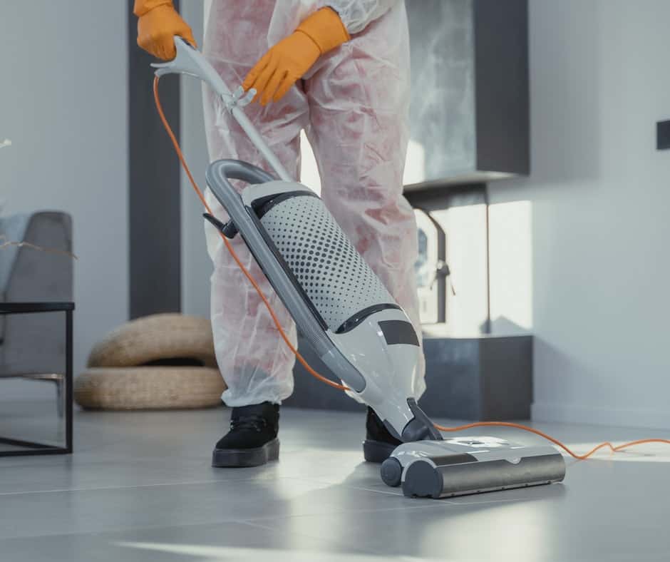 Someone vacuuming while wearing protective clothing