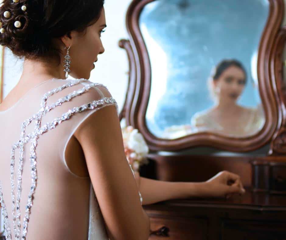 A bride looking at herself using a mirror on a dresser