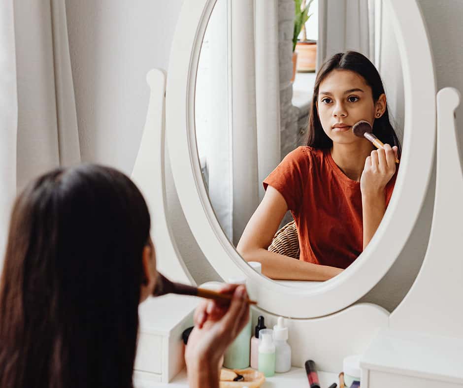 Girl using bedroom vanity and putting on makeup