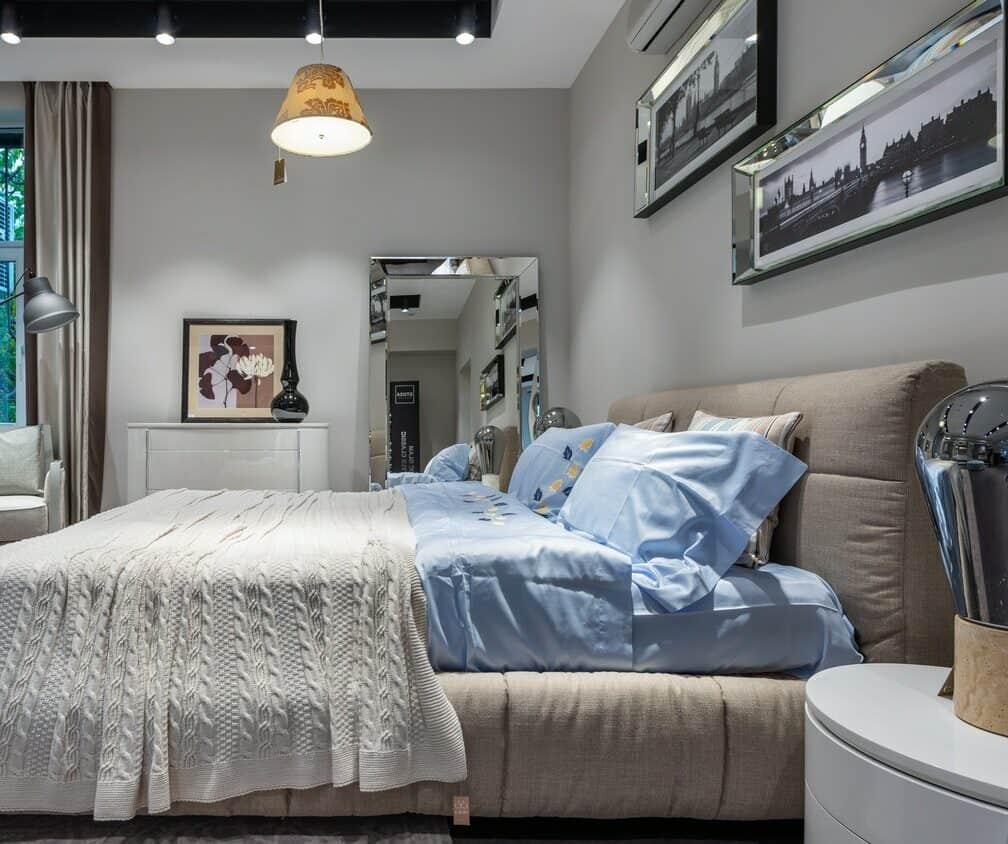 Blue bed sheet on gray bed in a gray-walled bedroom