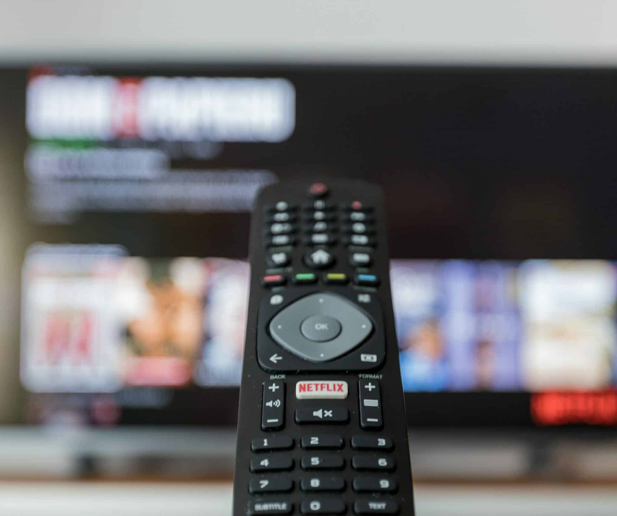 TV remote in front of blurred image of a TV