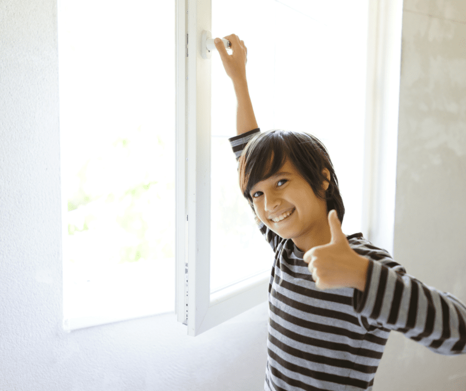 A young boy opening a window