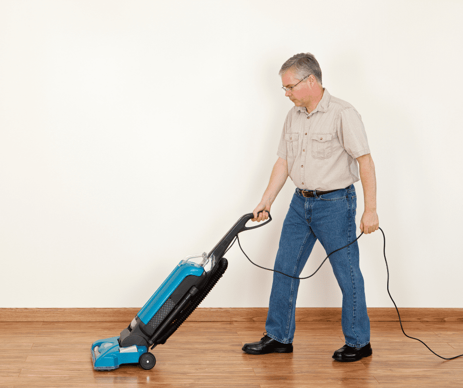 Man cleaning vinyl floor with bulky vacuum