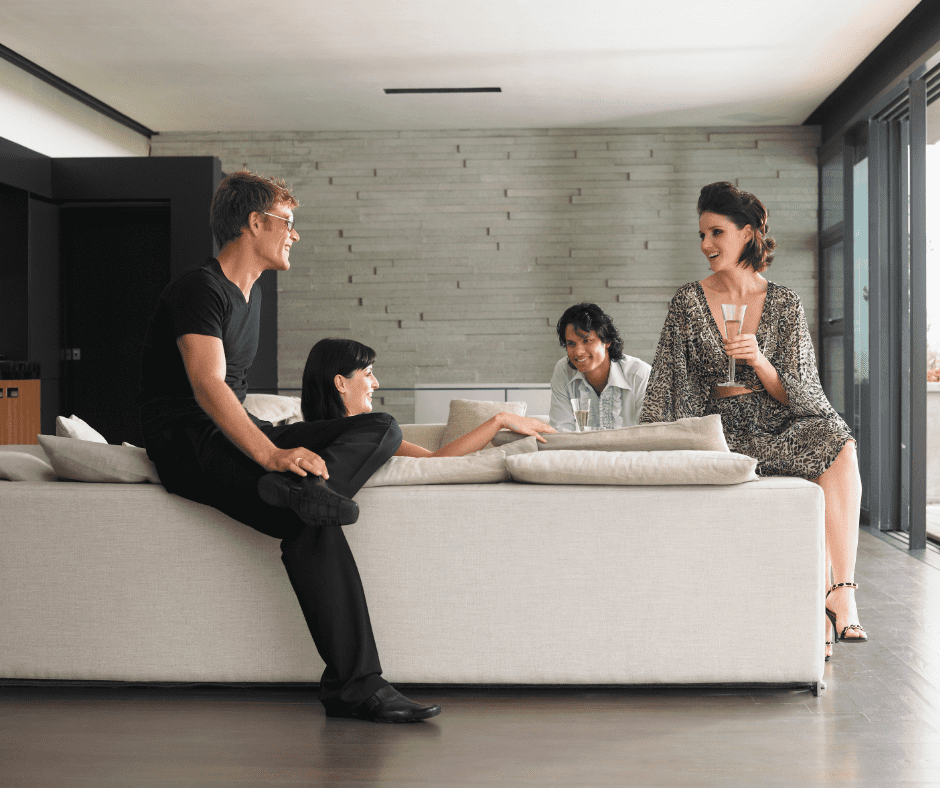 Four people sitting on a sectional sofa drinking champagne