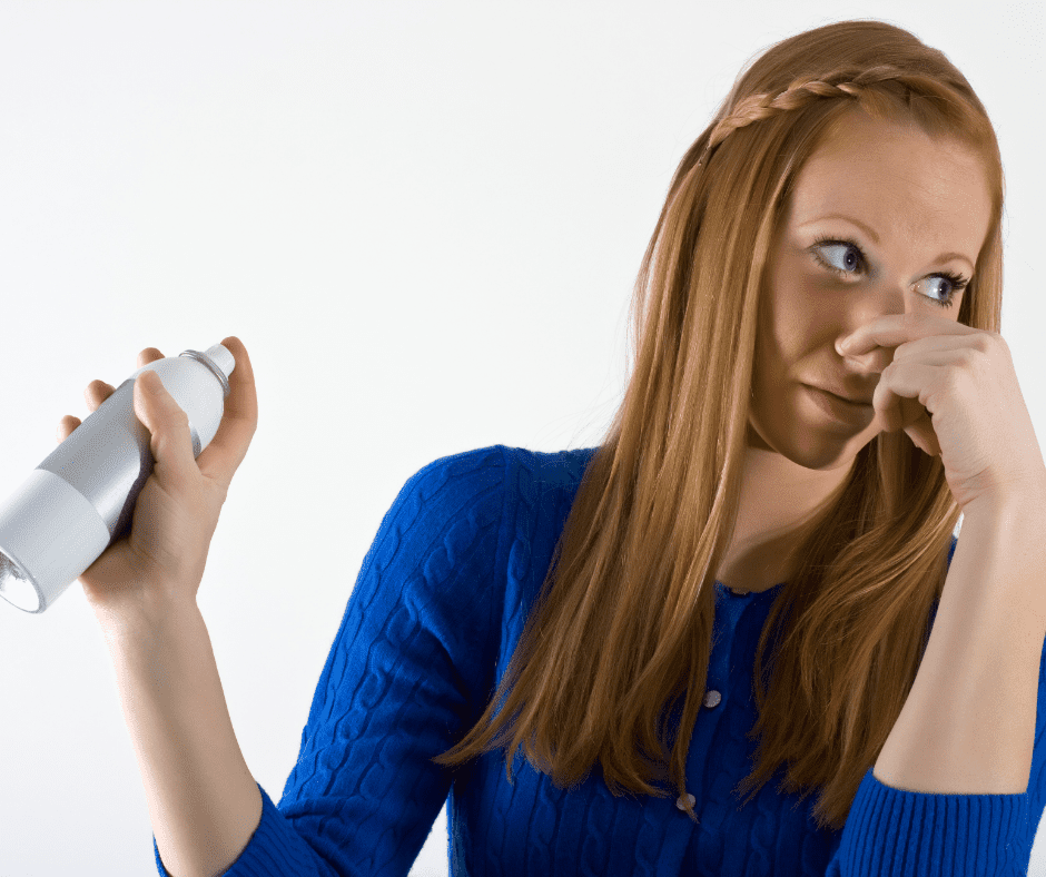 A lady holding a spray can obviously disgusted by a foul odor