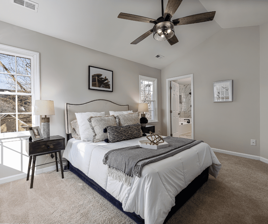 A white bedroom with a tall nightstand beside a white bed