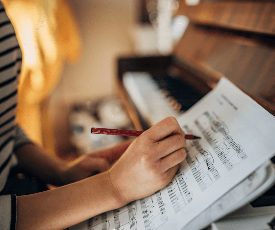 A woman writing music in front of a piano