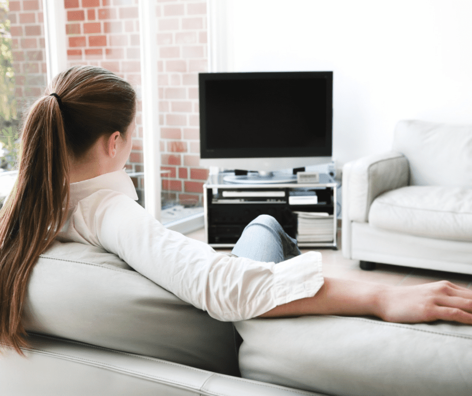 Woman sitting on a couch in front of the TV on a coffee table