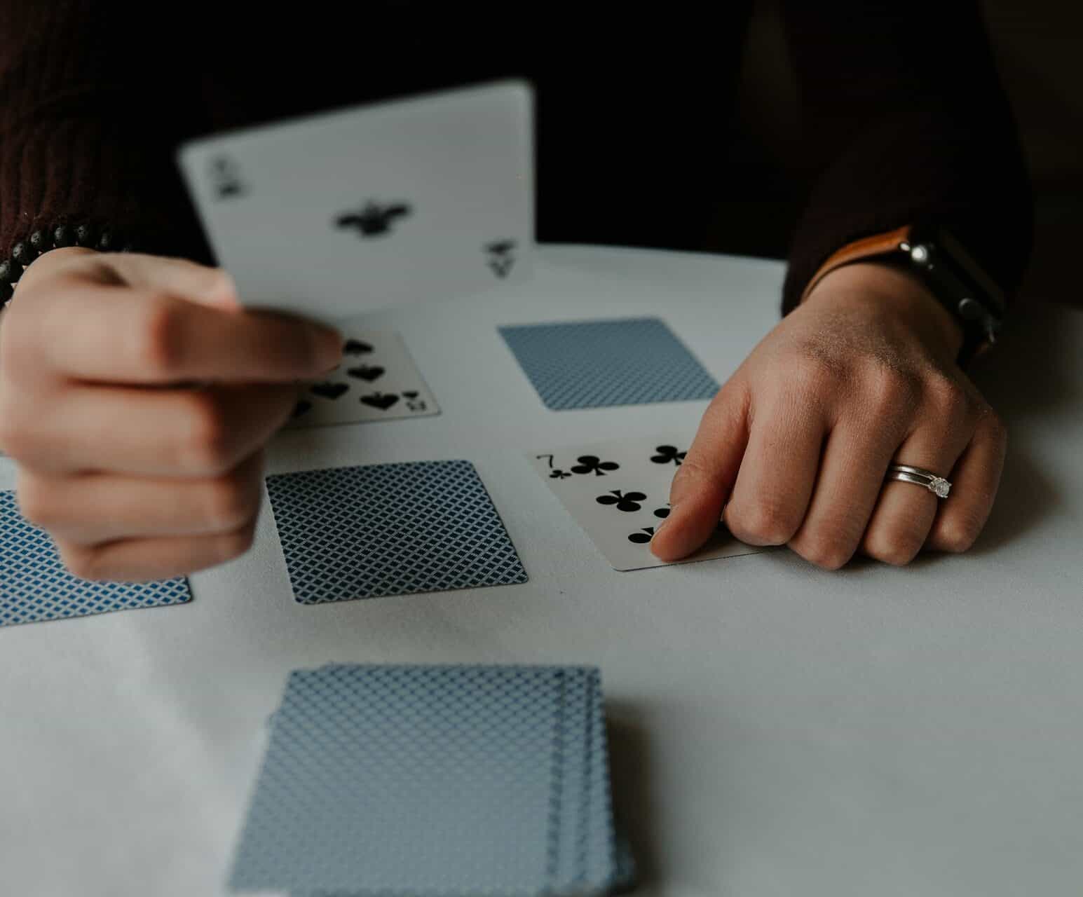 A person playing cards on table with white cloth