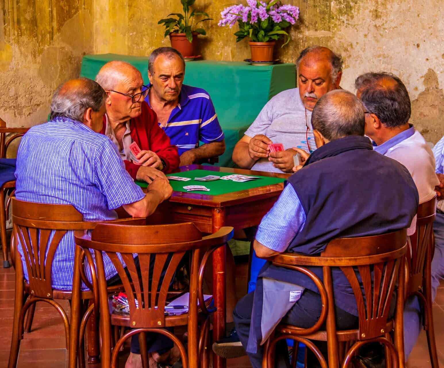 Group of aging men playing cards at a square table